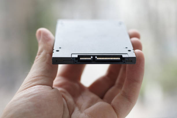 A close-up of a hand holding a modern solid-state drive (SSD) to illustrate advancements in SSD technology.