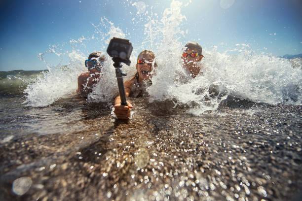 Three people in sunglasses capture thrilling water action with an action camera submerged in the waves.